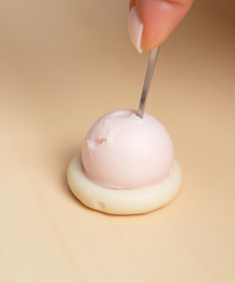 A scoop of pink ice cream placed on mochi dough